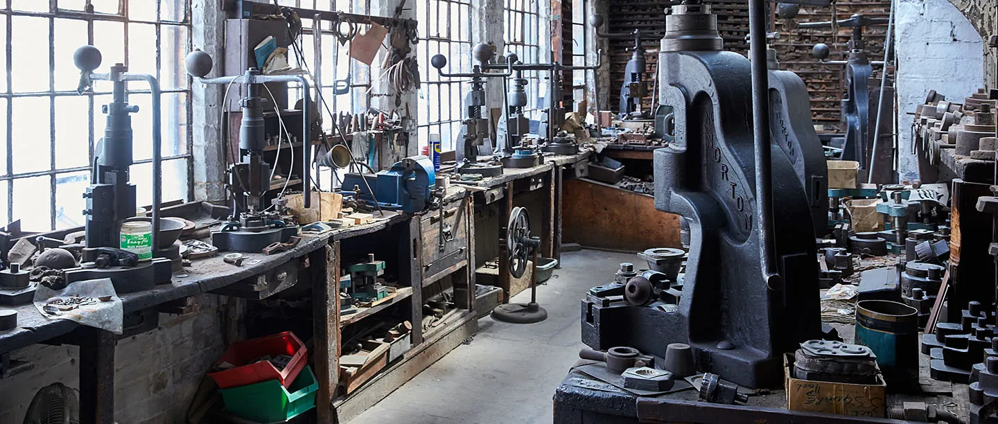 Rows of cast-iron fly presses and tools along the workbenches by the windows at the JW Evans Silver Factory