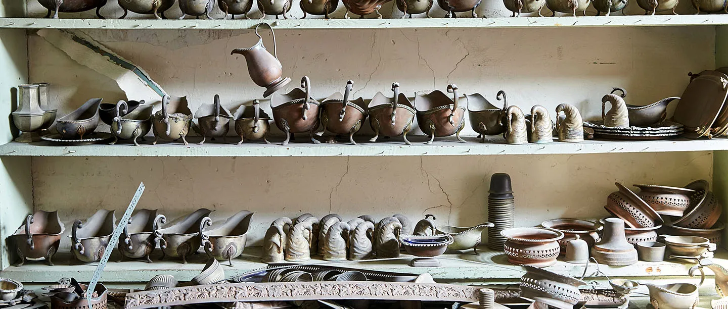 Shelves crowded with part-made sauce boats, jugs and pierced dishes at the JW Evans Silver Factory