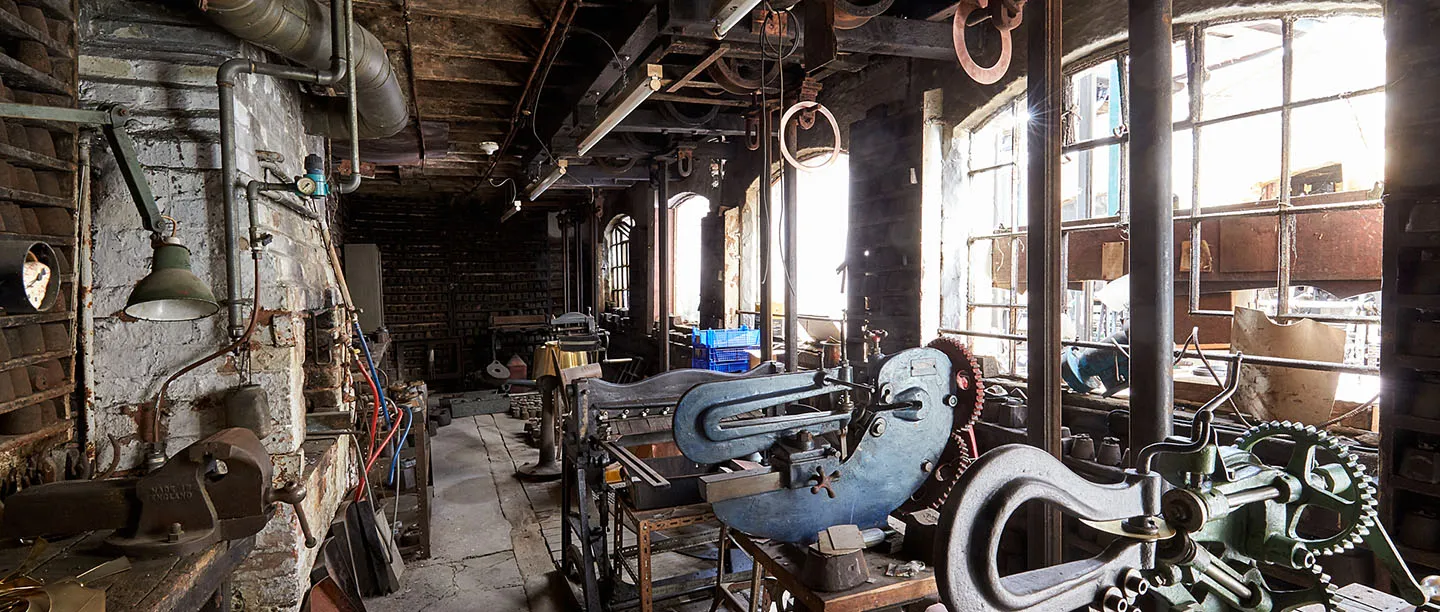 Heavy cutting machines, vices and overhead belting in a workshop at the JW Evans Silver Factory