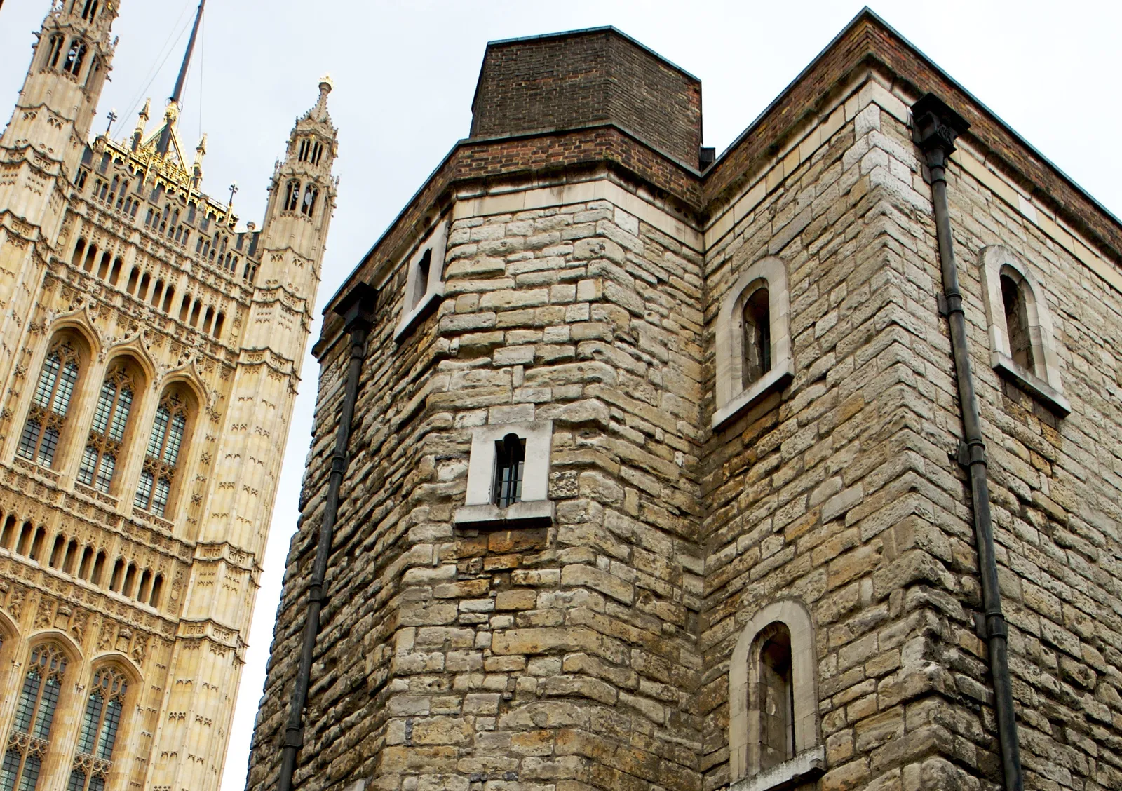 The rough stone corner of the Jewel Tower beside the carved Gothic stonework of the Victoria Tower