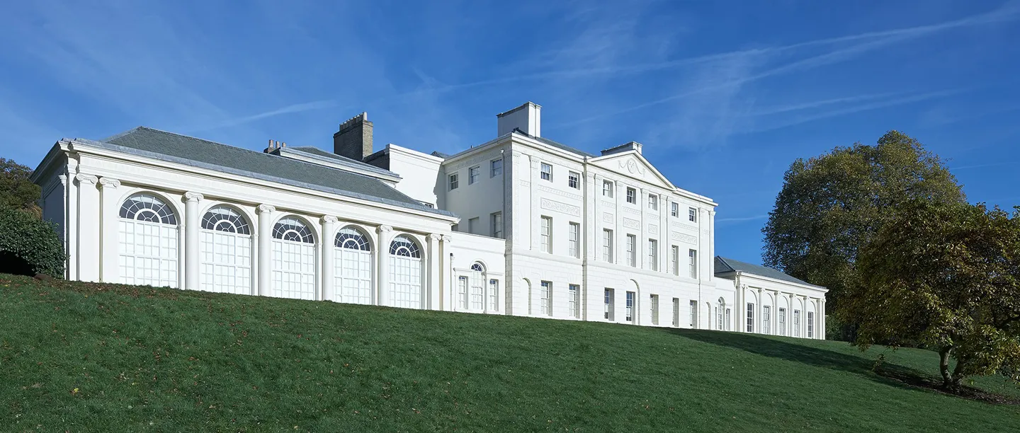 The white orangery and south front of the house under a deep blue sky