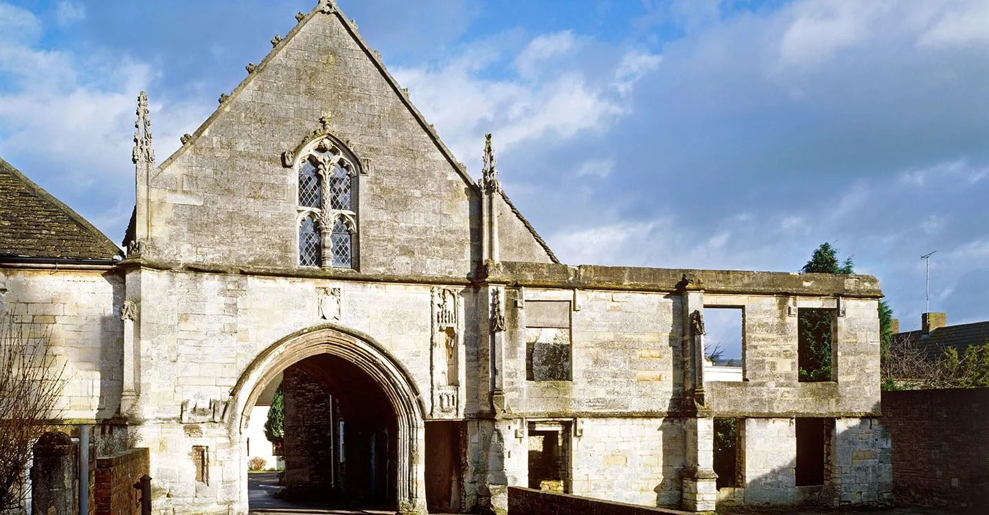 Kingswood Abbey Gatehouse, a Tudor stone gatehouse with a tall traceried window above a moulded archway, in winter sun