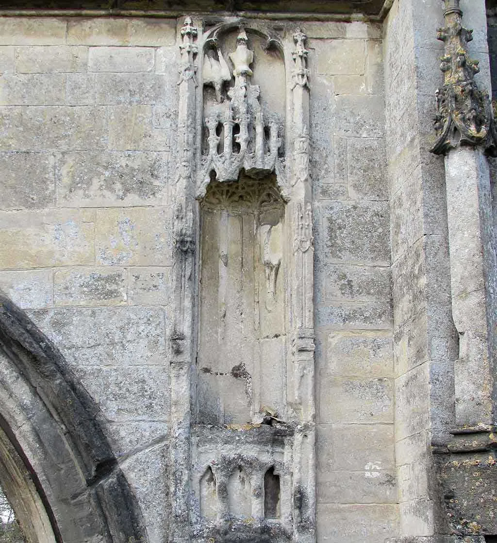 A carved niche beside the archway of Kingswood Abbey Gatehouse, with a canopy of pinnacles and a lily pot