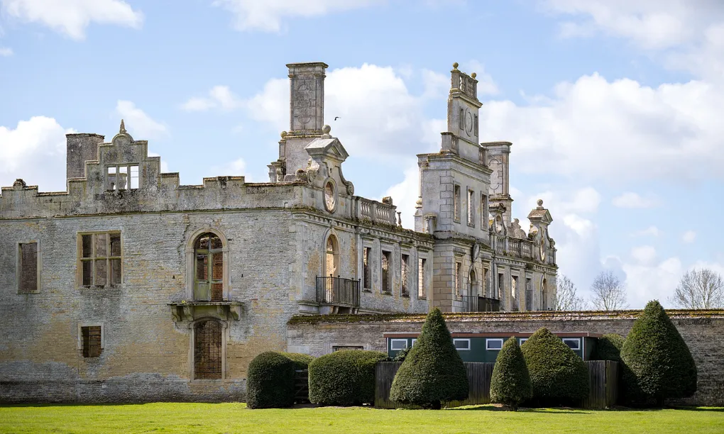 The ruined north range of Kirby Hall with its ornate gables and chimneys above clipped yews