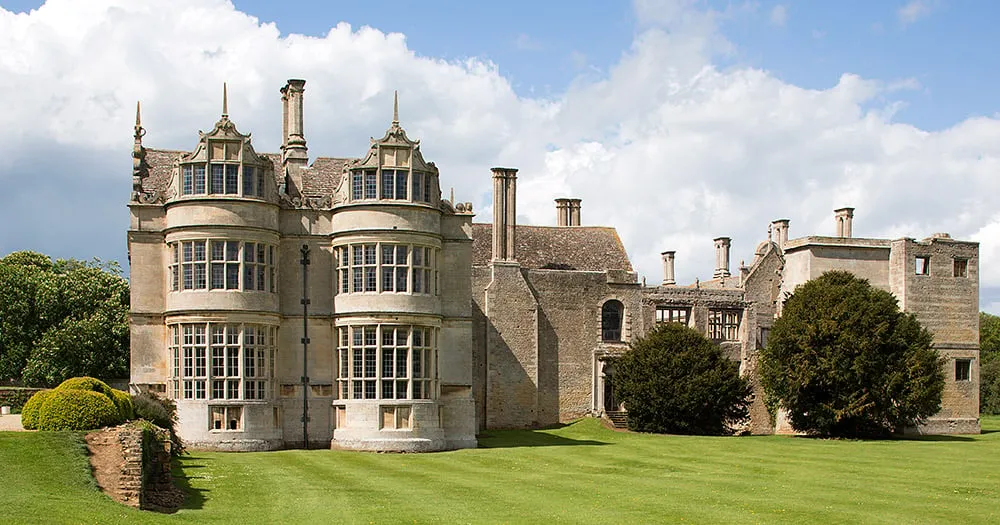 The two-storey bay windows of the west front beside the roofless ranges of the hall