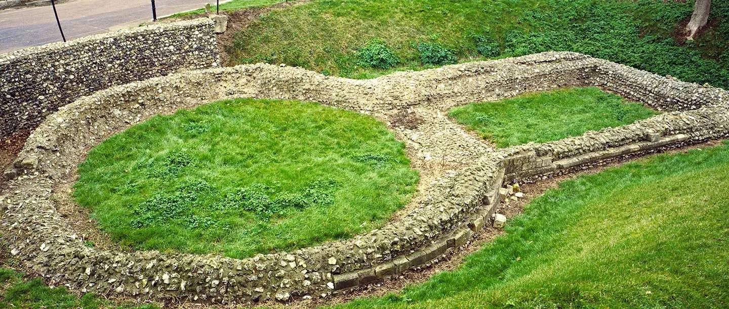 The flint foundations of the Knights Templar church in Dover, a round nave and rectangular chancel outlined on a grassy slope