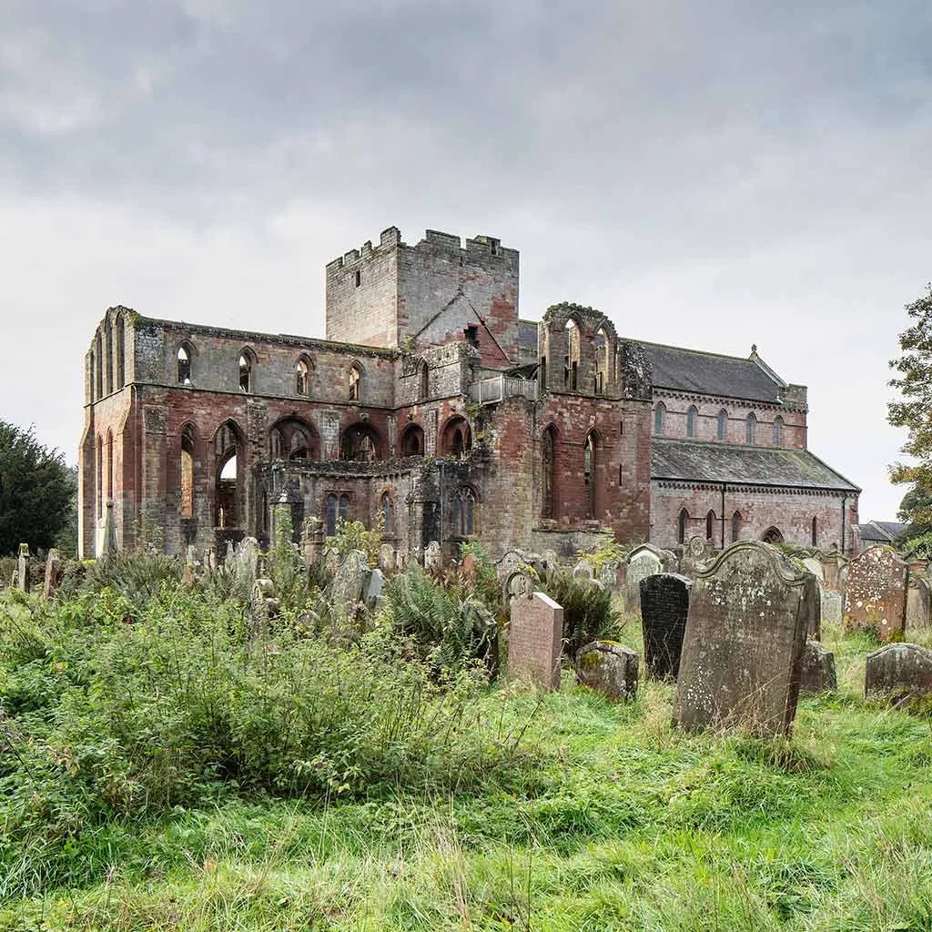 The priory church seen across the overgrown graveyard