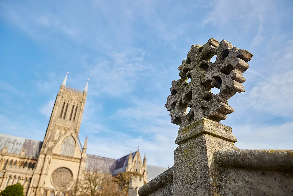 A carved stone finial on the palace parapet with Lincoln Cathedral's central tower and rose window beyond