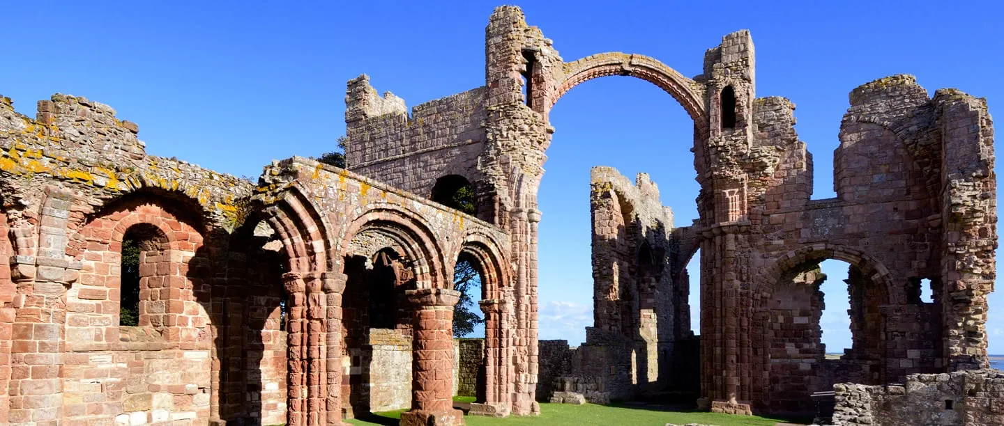 The red sandstone arcades and the rainbow arch of the priory church under a deep blue sky