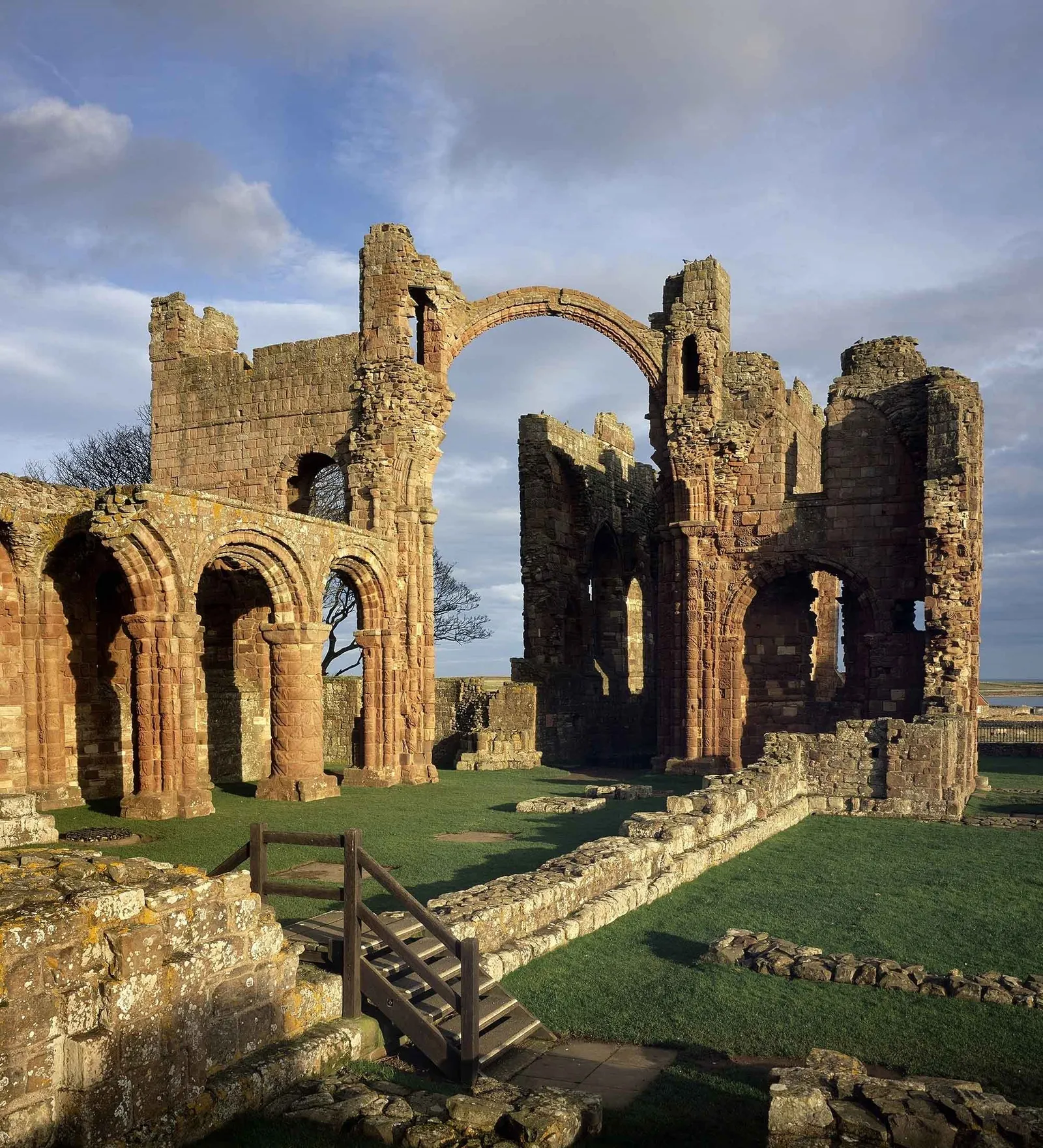 Round-arched nave arcades and the rainbow arch lit by low sun under a stormy sky