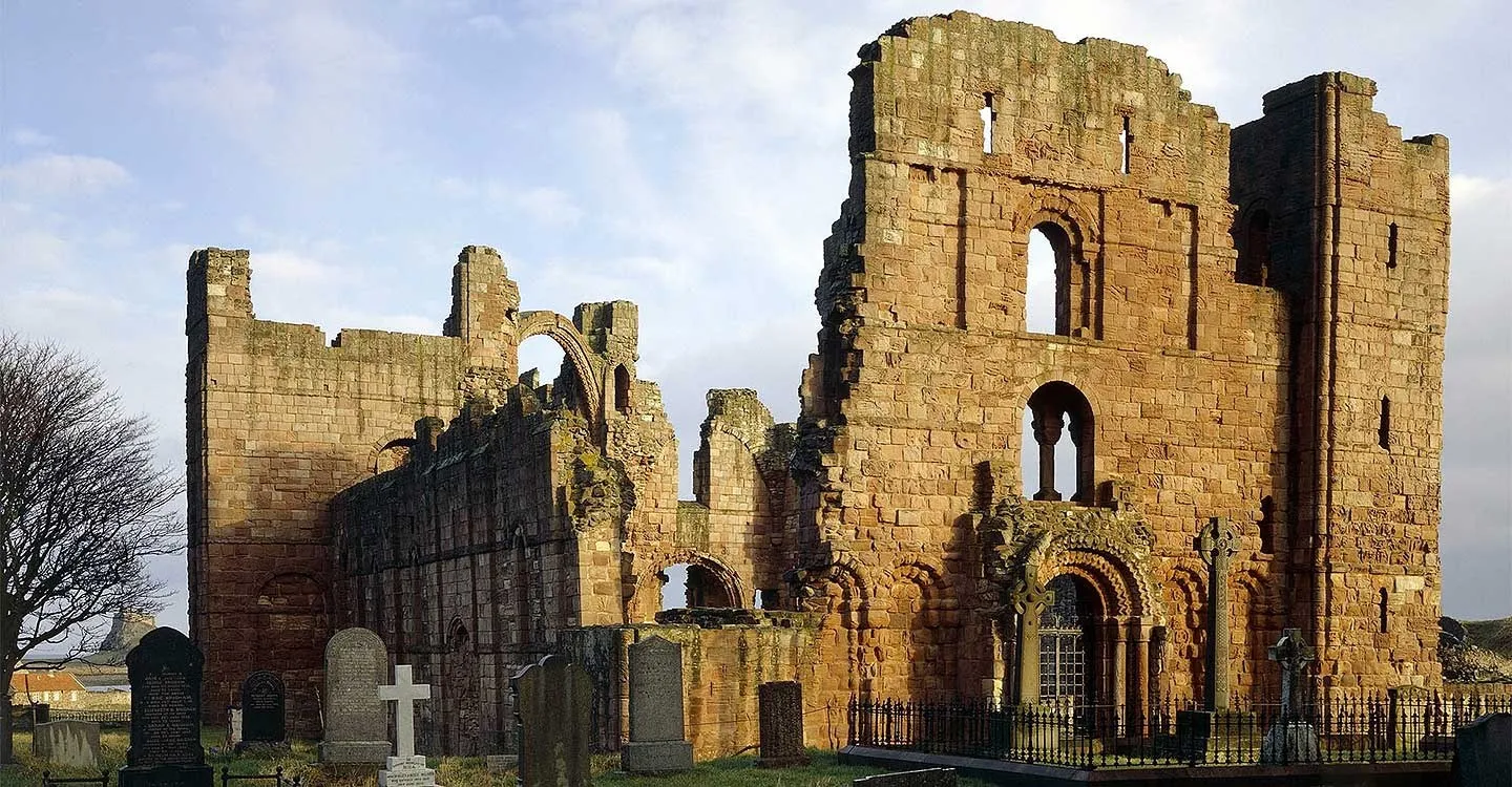 The west front's carved Norman doorway behind the churchyard crosses in winter sun