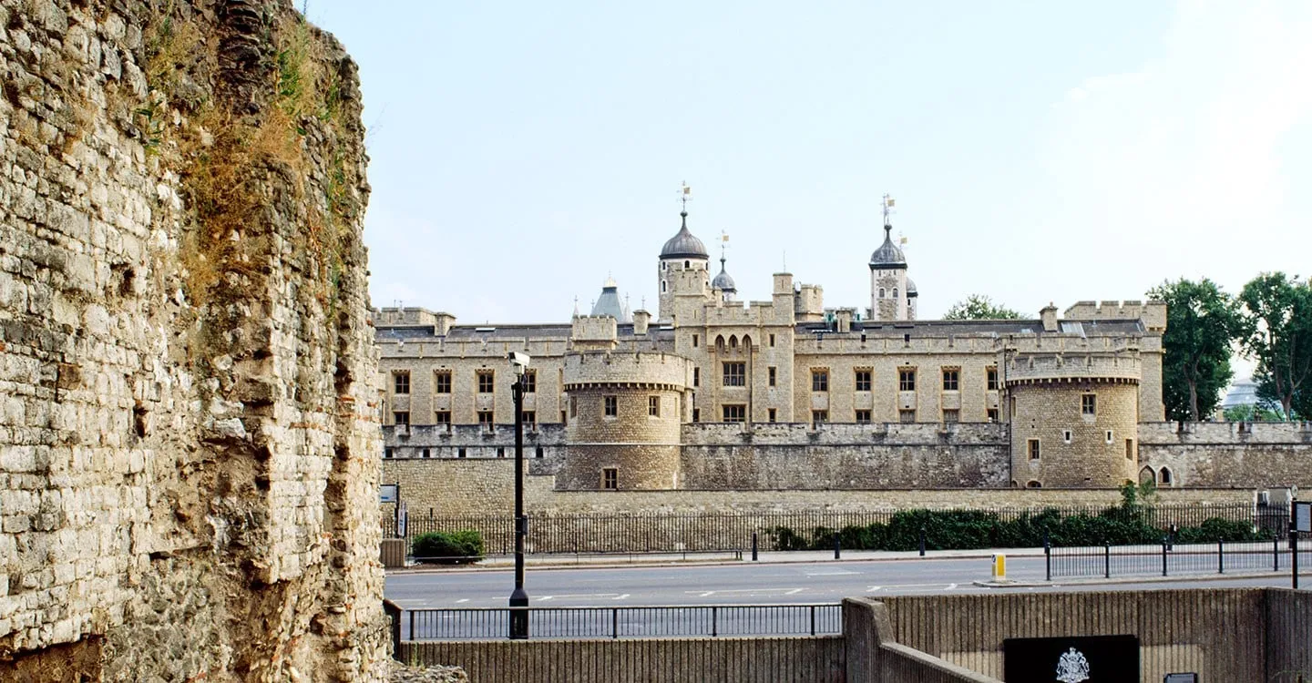 The weathered end of London Wall with the Tower of London beyond, across the road