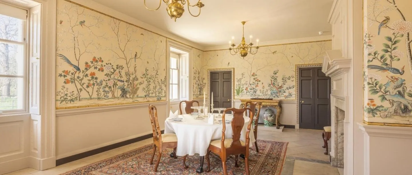Marble Hill's dining room with hand-painted Chinese wallpaper of birds and flowers, a laid round table and brass chandelier