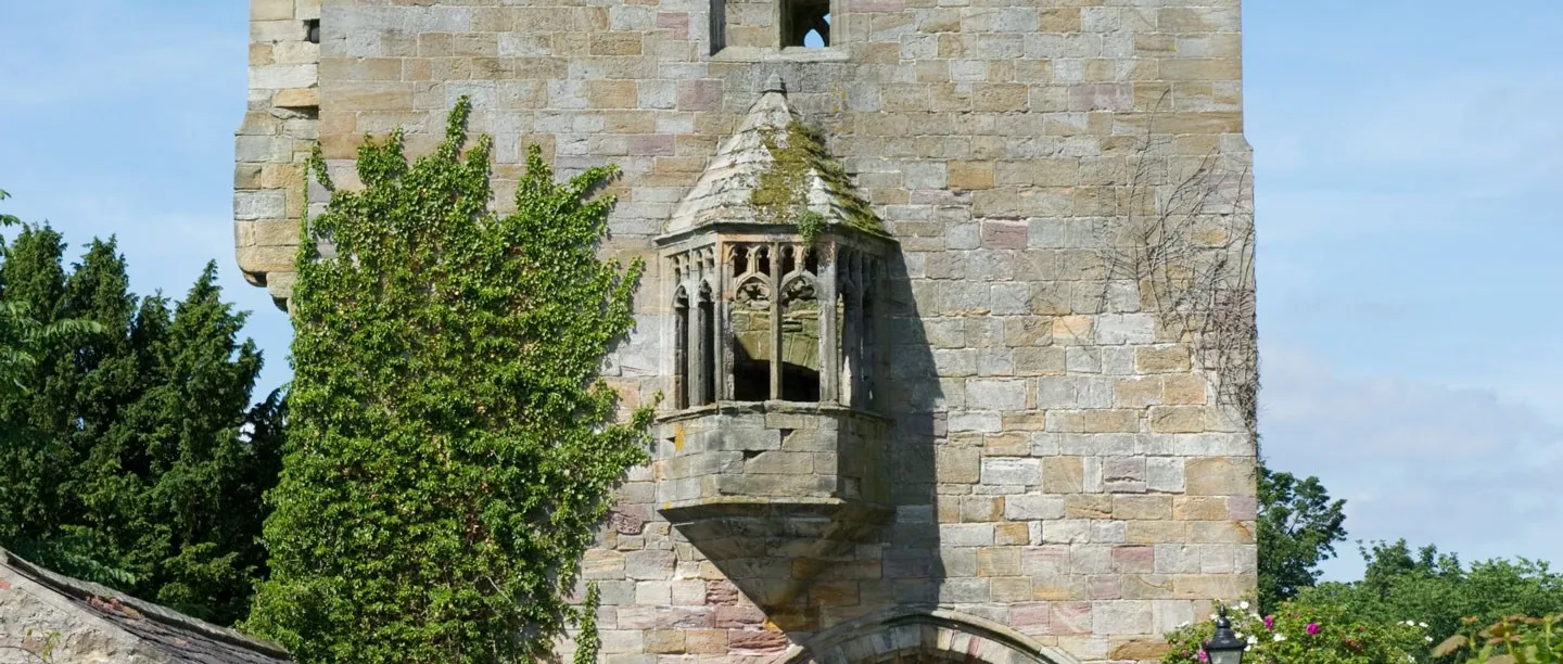 Close-up of the carved stone oriel window on the front of Marmion Tower, with ivy on the wall