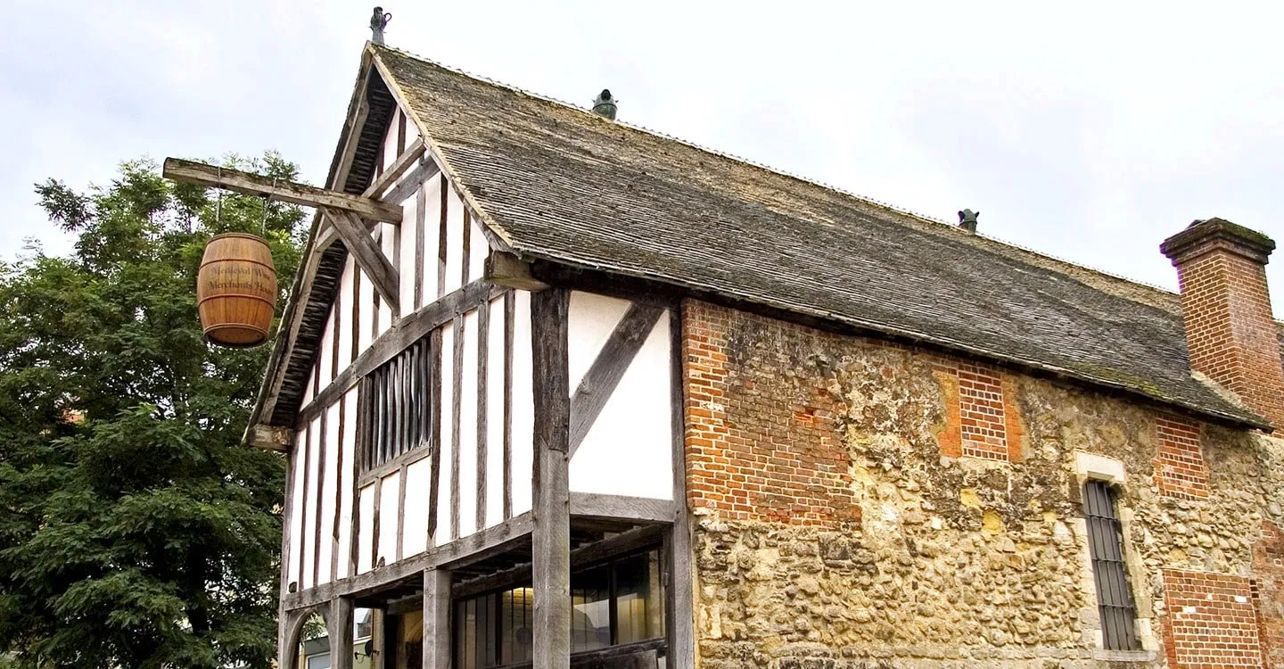 The timber-framed gable, hanging barrel sign and stone and brick side wall of Southampton's Medieval Merchant's House