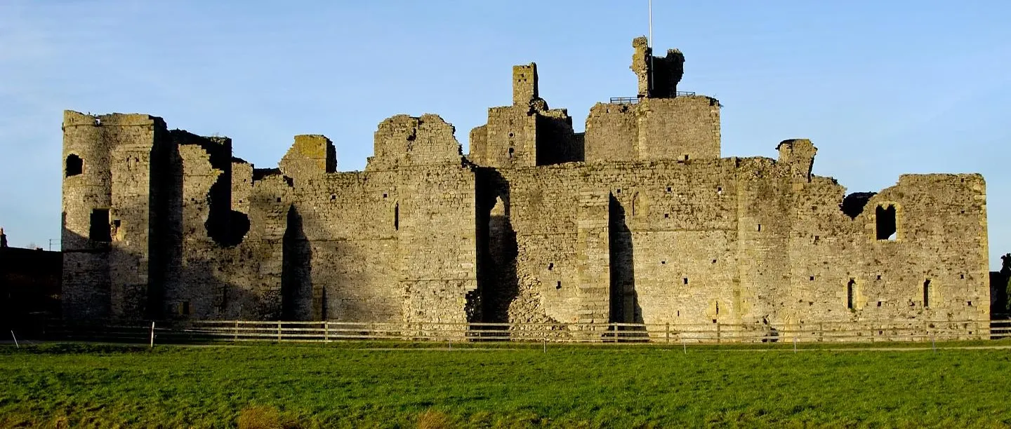 The east side of Middleham Castle's curtain wall and keep lit by low sun