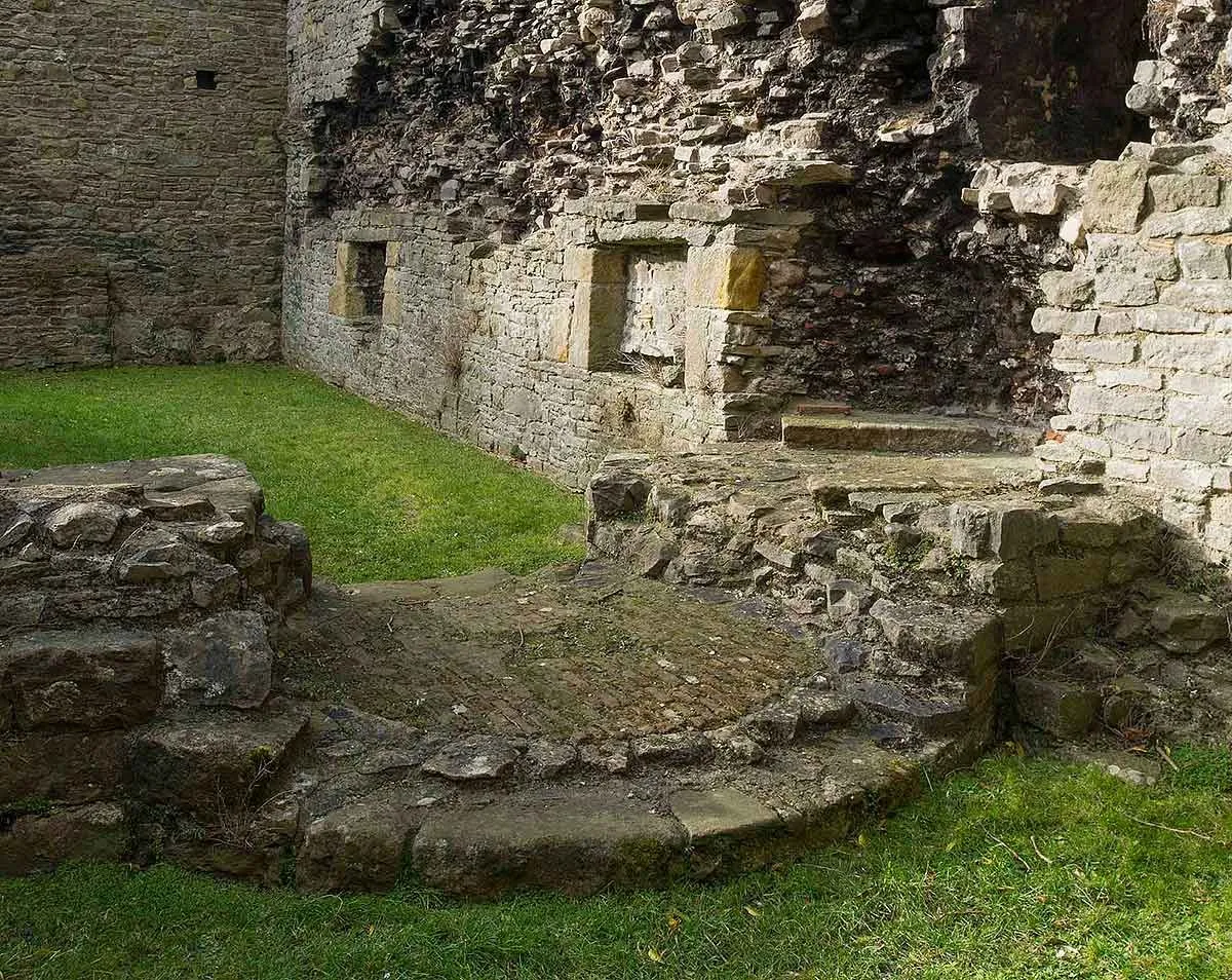 Low walls and stone steps of the west range around a grassy court