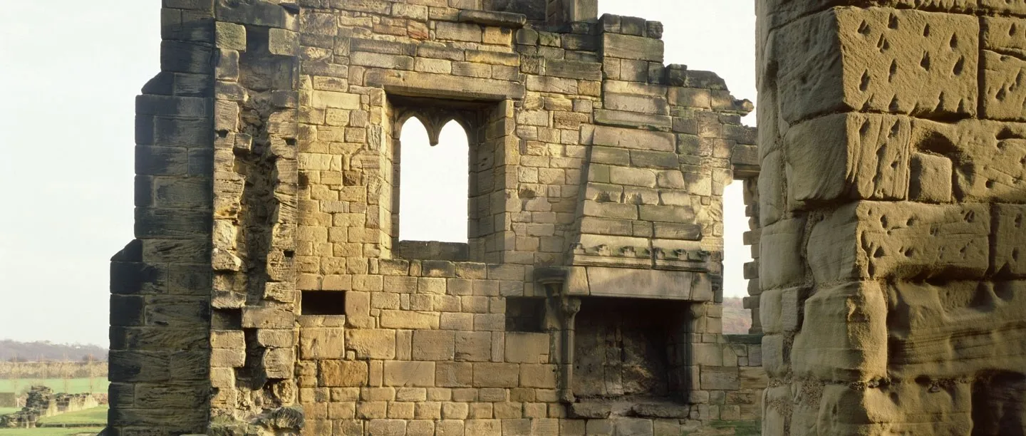 A ruined sandstone wall of the prior's lodging at Monk Bretton Priory, with a traceried window opening above a carved stone fireplace