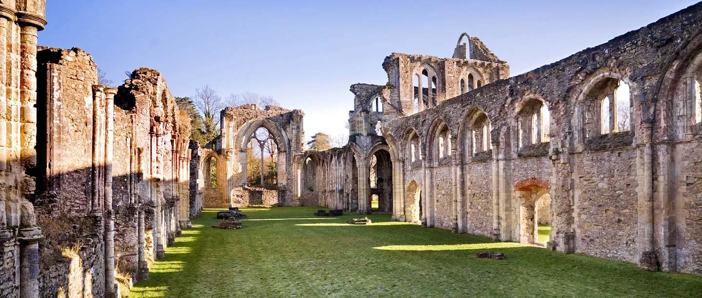 The long roofless nave of Netley Abbey, its arcades lit by low sun on the grass