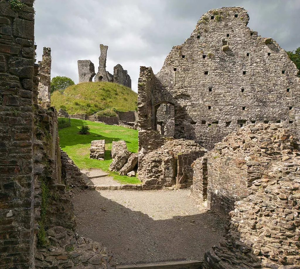 The motte and ruined keep of Okehampton Castle seen through the walls of the inner gatehouse