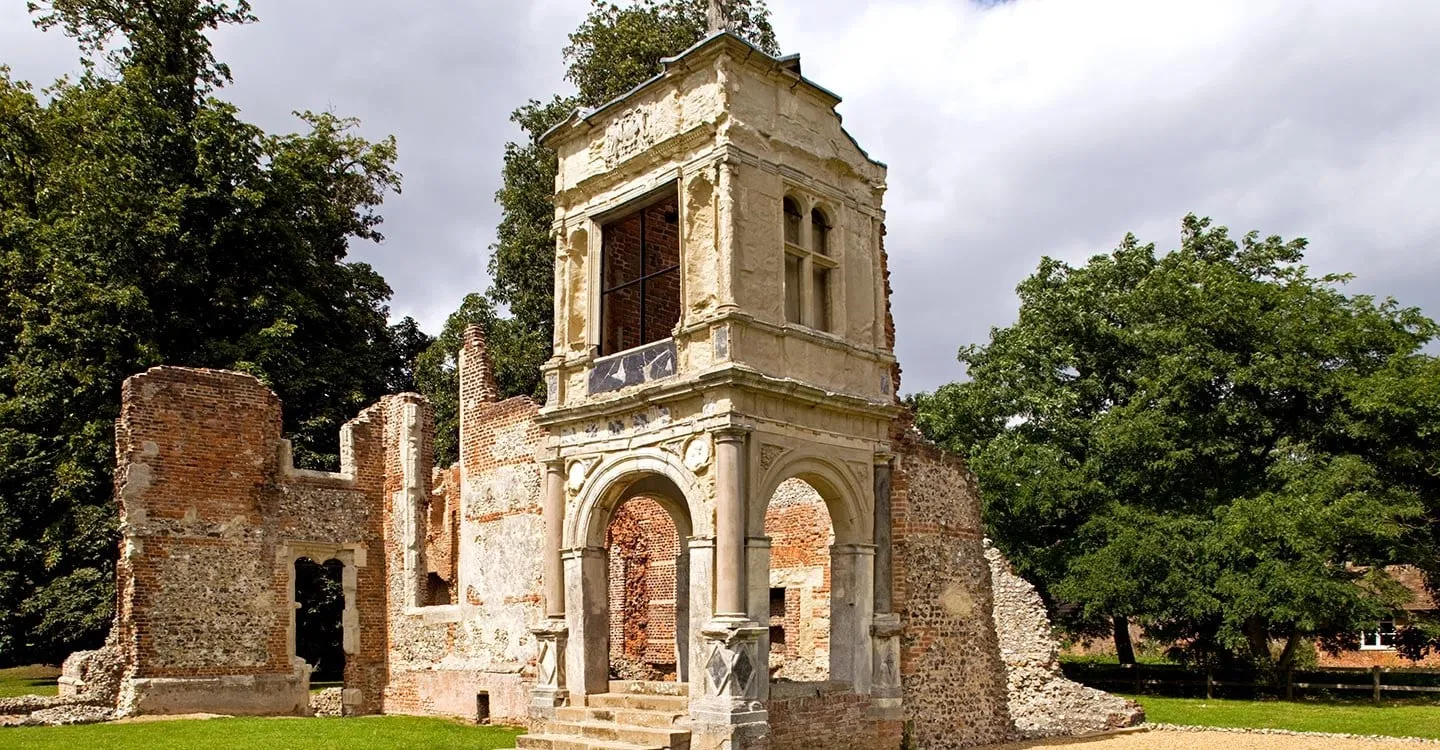 The two-storey stone porch of Old Gorhambury House, with classical columns and arches, among ruined brick and flint walls
