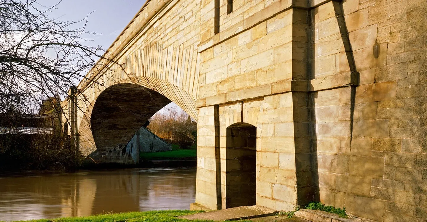 The sandstone arch and pier of Over Bridge, Thomas Telford's bridge over the River Severn, in low winter sun