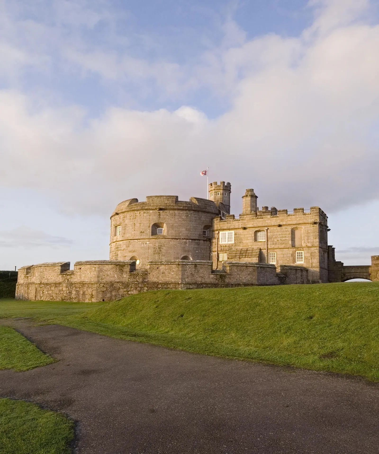 The Tudor keep and gatehouse in warm evening light above a curving path