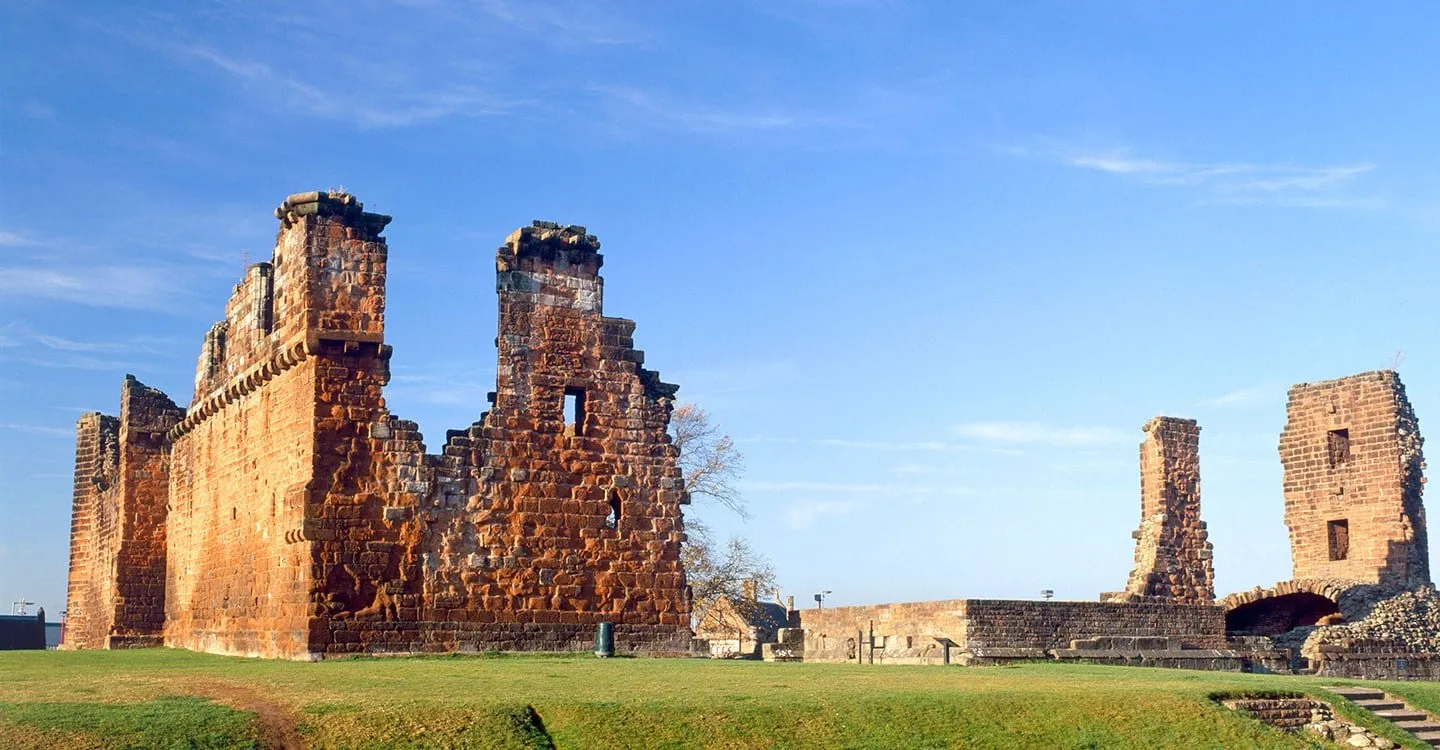 The red sandstone walls of Penrith Castle glowing in low winter sun under a blue sky, with grass in front