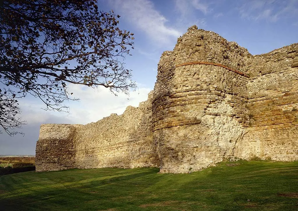 The Roman walls of the Saxon Shore fort, with a bastion and bands of red tile, in low sun