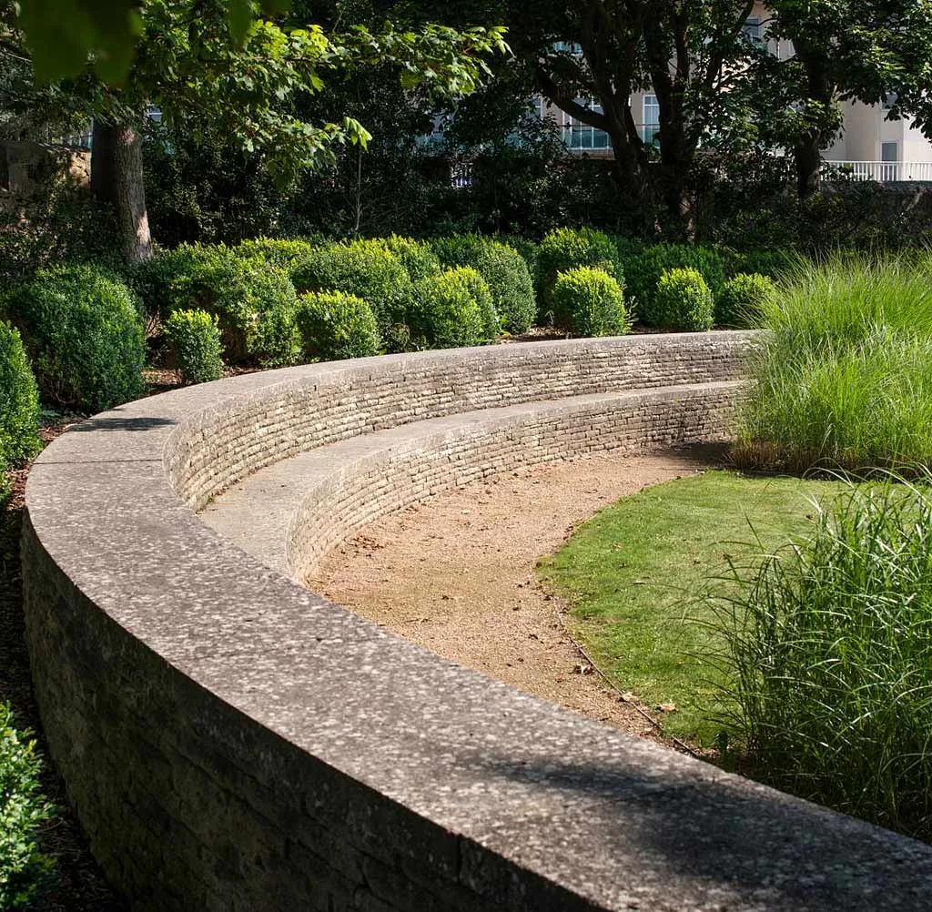 A curving stone seat wall in the castle's contemporary garden, among clipped box and grasses