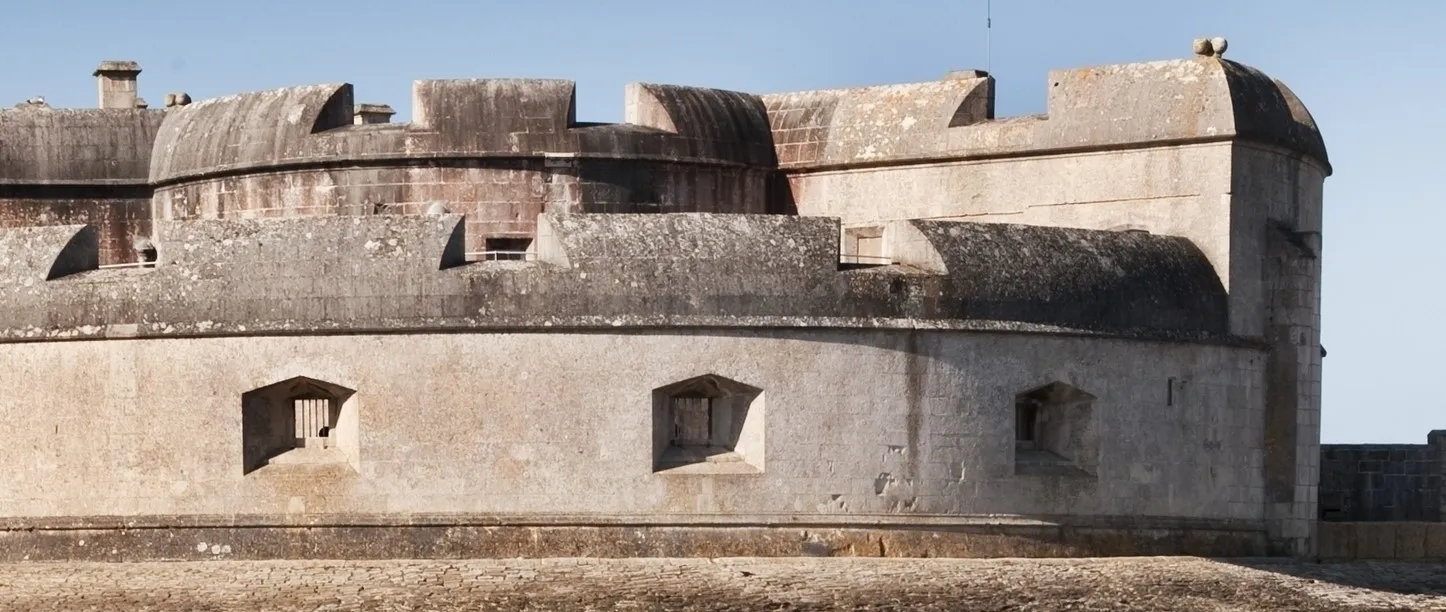 The curved gun battery and squat Tudor walls of Portland Castle in morning sun