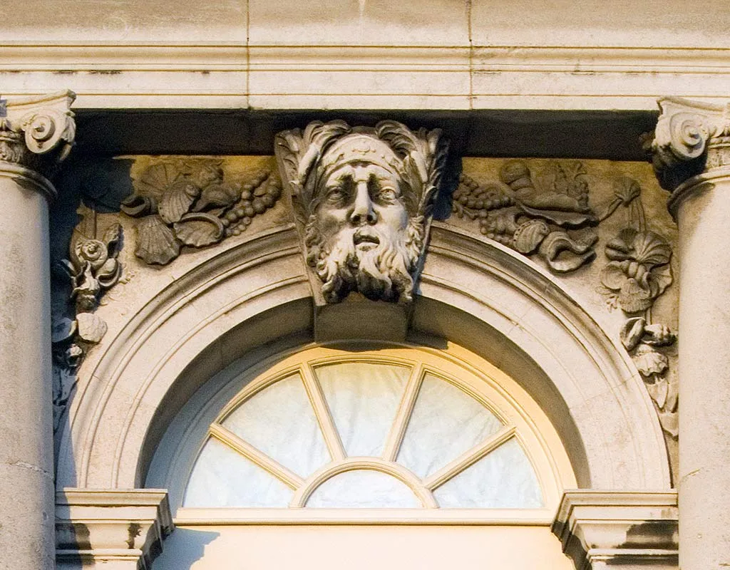 A carved stone keystone of a bearded sea god above the fanlight of Ranger's House, flanked by shells, fruit and Ionic capitals