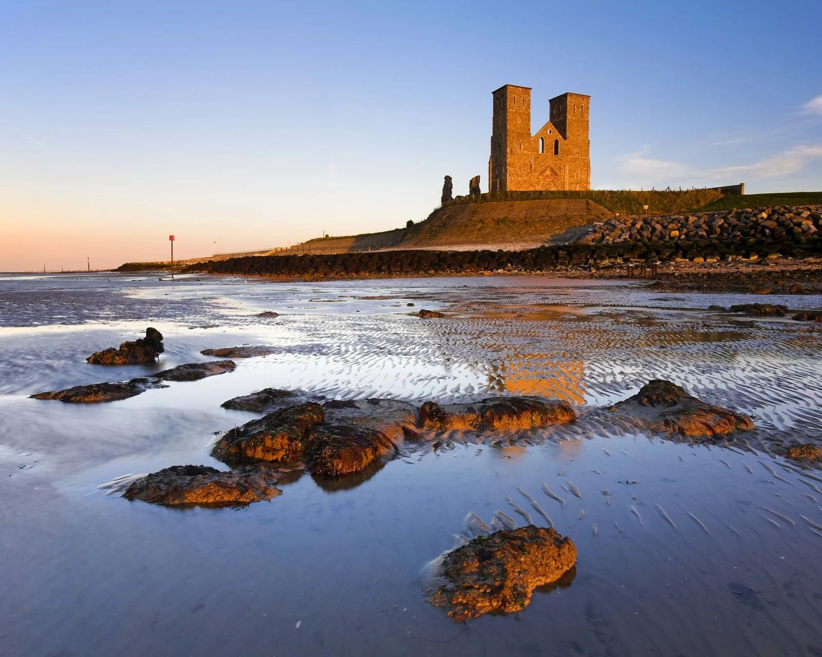 The towers glowing at sunset above the rocks and rippled sand at low tide
