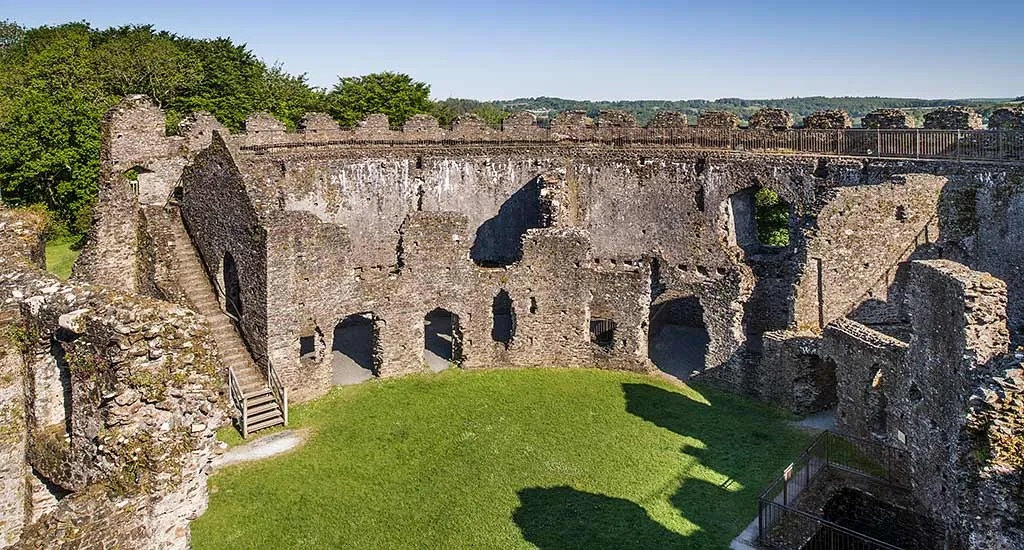 The inner ward of Restormel's keep, with a stair climbing to the wall walk and ruined rooms around the lawn