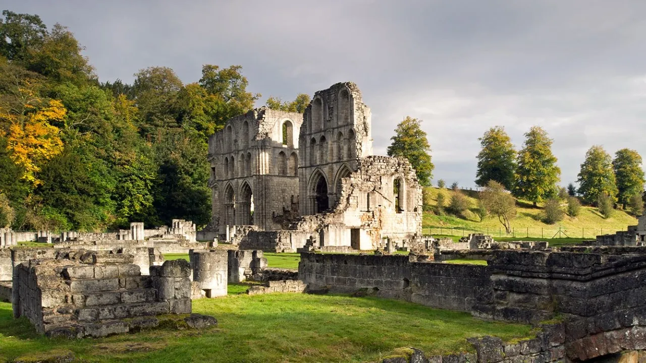 The tall ruined transepts of Roche Abbey in autumn light, with low walls of the abbey buildings in front