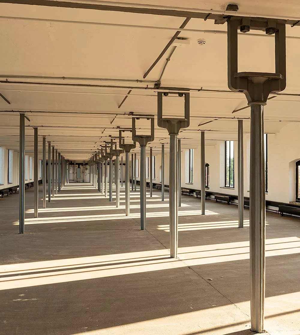 The restored third floor of the main mill at Shrewsbury Flaxmill Maltings, rows of slender cast-iron columns casting stripes of sunlight