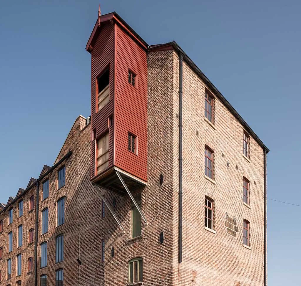 The red timber hoist house projecting from the brick engine house at Shrewsbury Flaxmill Maltings, against a deep blue sky