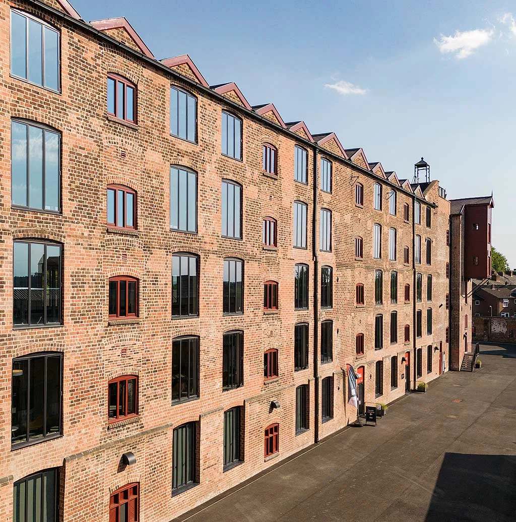 The long red-brick facade of the restored main mill at Shrewsbury Flaxmill Maltings, rows of tall windows above an empty yard