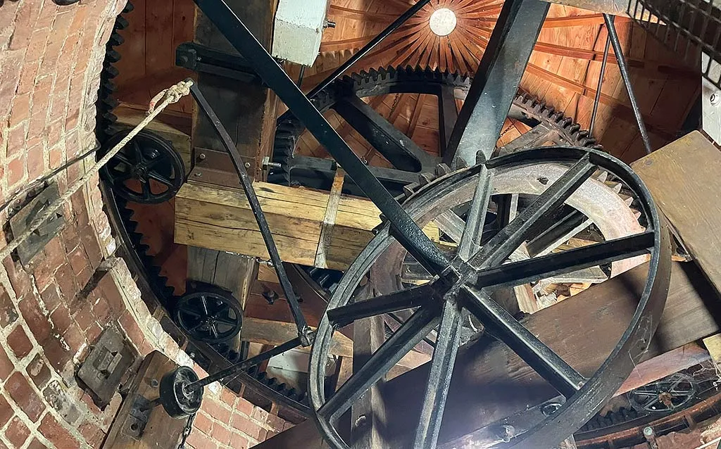 Cast-iron gear wheels and timber beams inside the cap of Sibsey Trader Windmill, under a radiating wooden ceiling