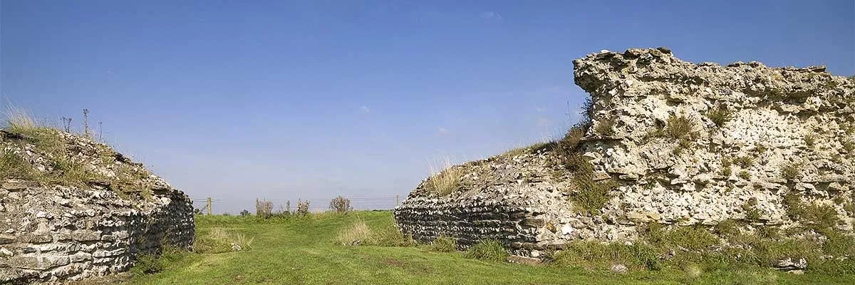 The gap of Silchester's Roman south gate between two ends of the flint town wall, with grassland beyond