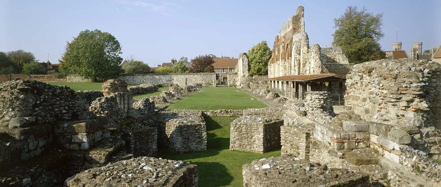 Excavated foundations of the abbey church with the nave wall and covered walkway beyond
