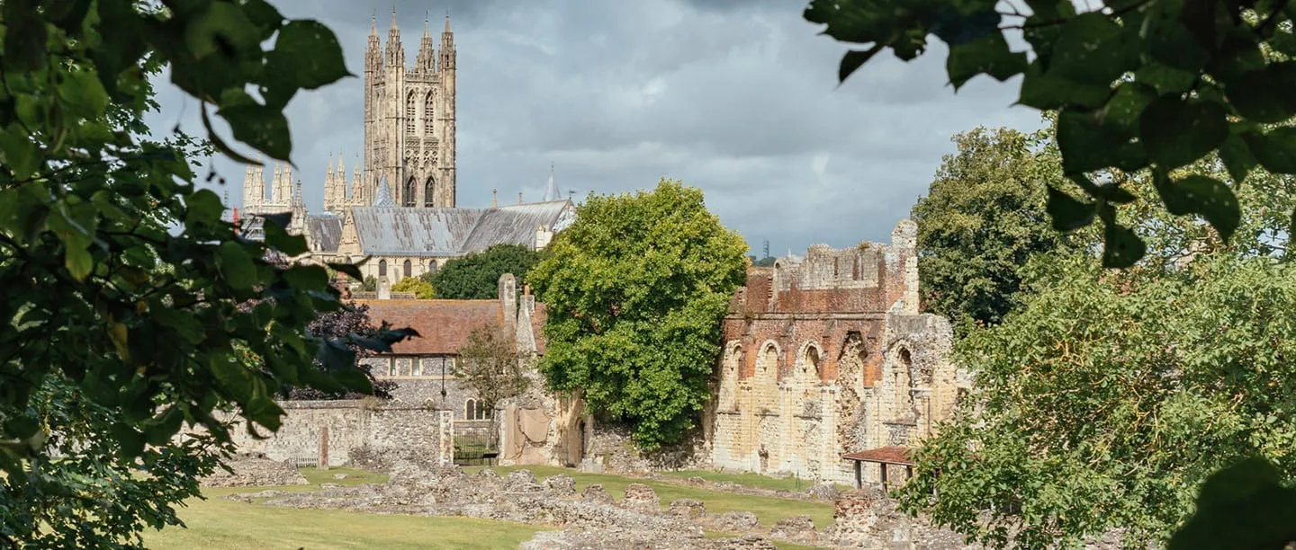 Canterbury Cathedral's Bell Harry tower seen through leaves above the abbey ruins