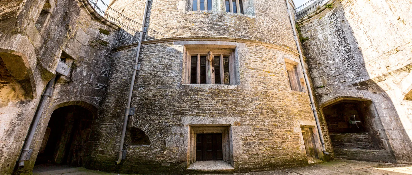 St Mawes Castle's inner courtyard, with the round keep's stone walls and a cannon in a vaulted embrasure