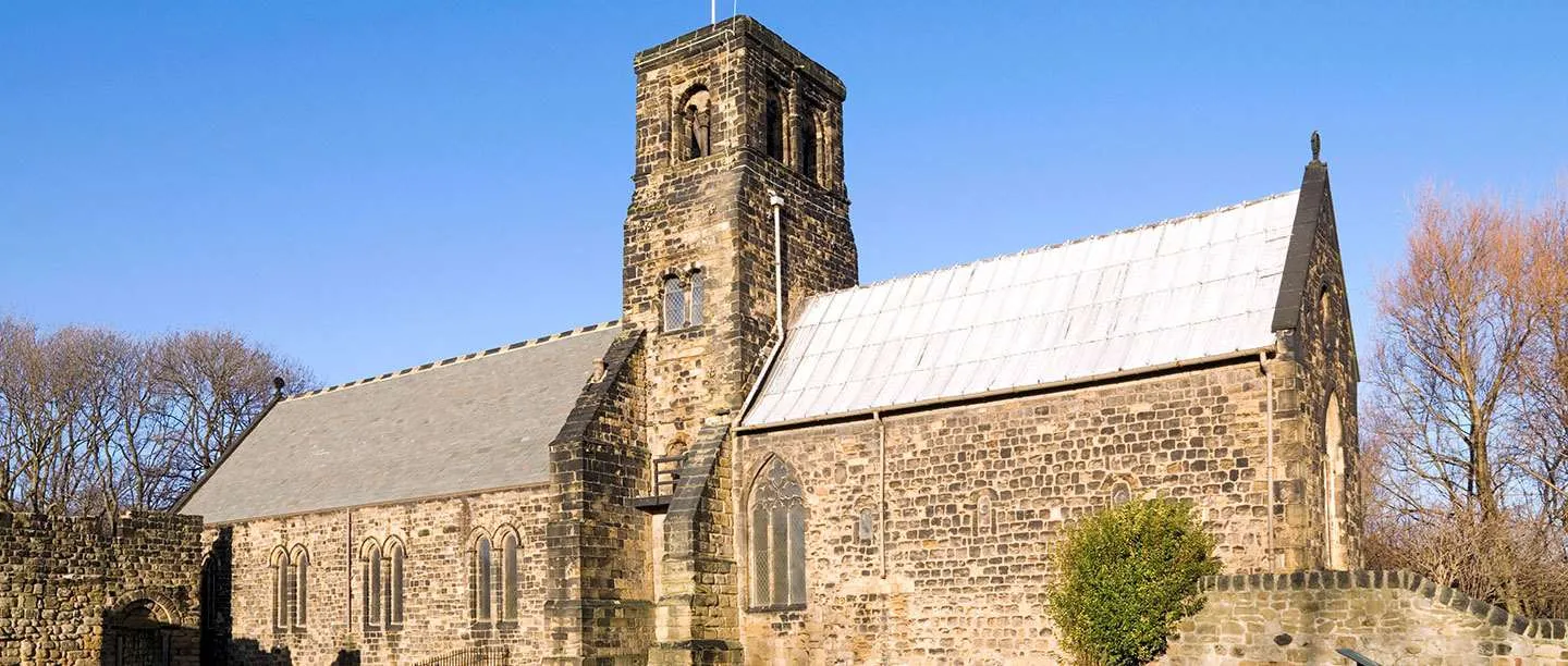 St Paul's Church at Jarrow, with its Anglo-Saxon tower and chancel beside the ruined monastery walls, under a clear blue sky