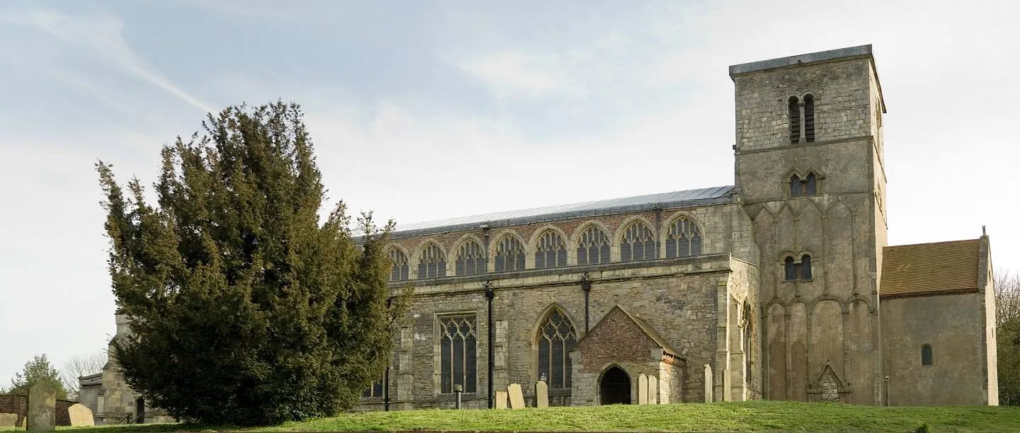 St Peter's Church, Barton-upon-Humber, its long Gothic nave and Anglo-Saxon tower above a grassy churchyard with old headstones and a yew