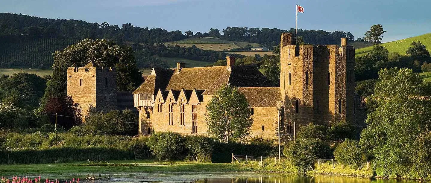 The south tower and great hall glowing in evening light across the pool