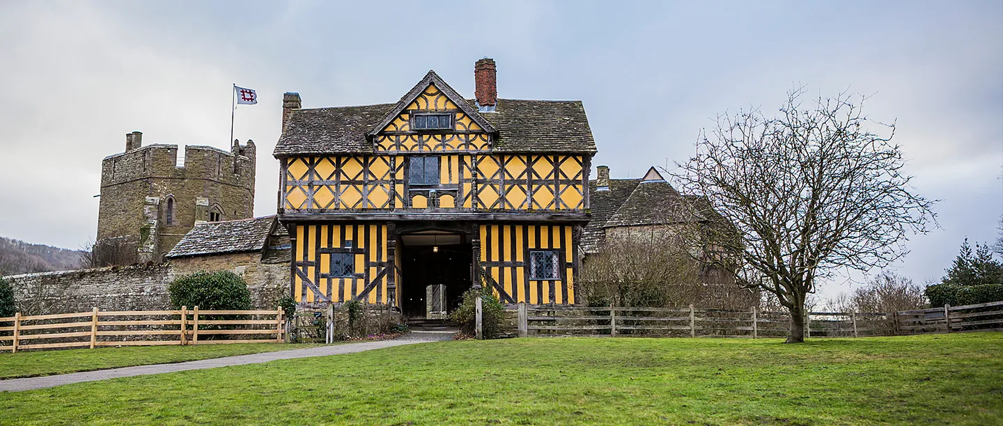 The timber-framed gatehouse and the south tower with its English Heritage flag on a grey winter day