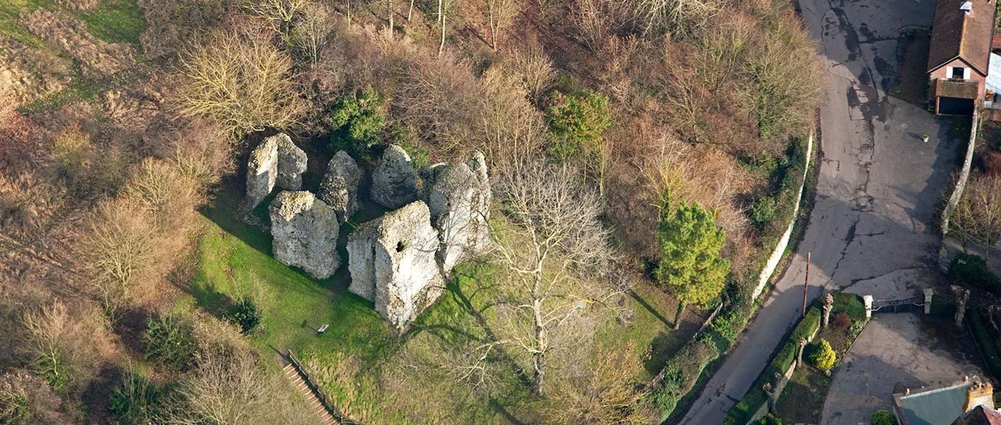Aerial view of the ruined flint keep of Sutton Valence Castle among winter trees, with steps up from the village lane