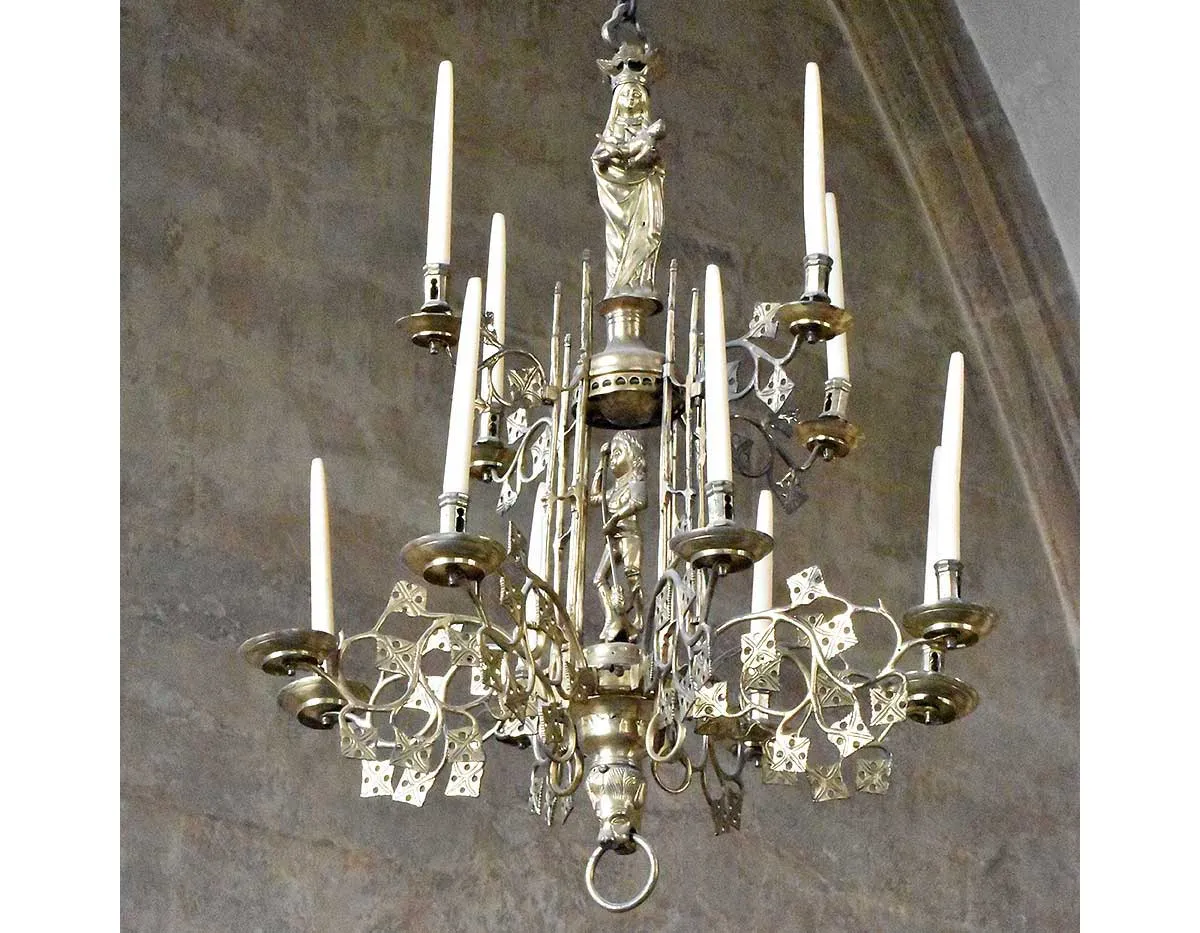 A medieval brass chandelier from Temple Church with candles, leafy branches and small figures of the Virgin and St George