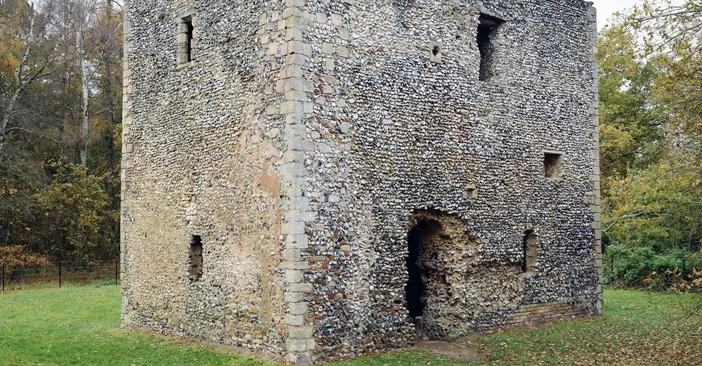 The flint walls and stone quoins of Thetford Warren Lodge, a two-storey medieval lodge among autumn trees